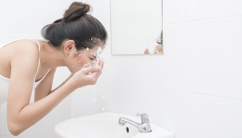 Kobiet myje twarz w łazience oszczędzając wodę