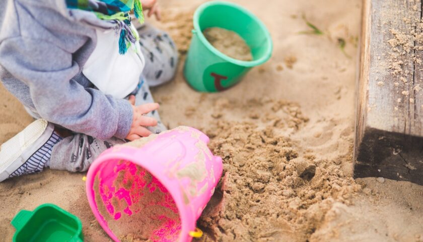Dziewczynka bawi się kolorowymi zabawkami w piaskowicy